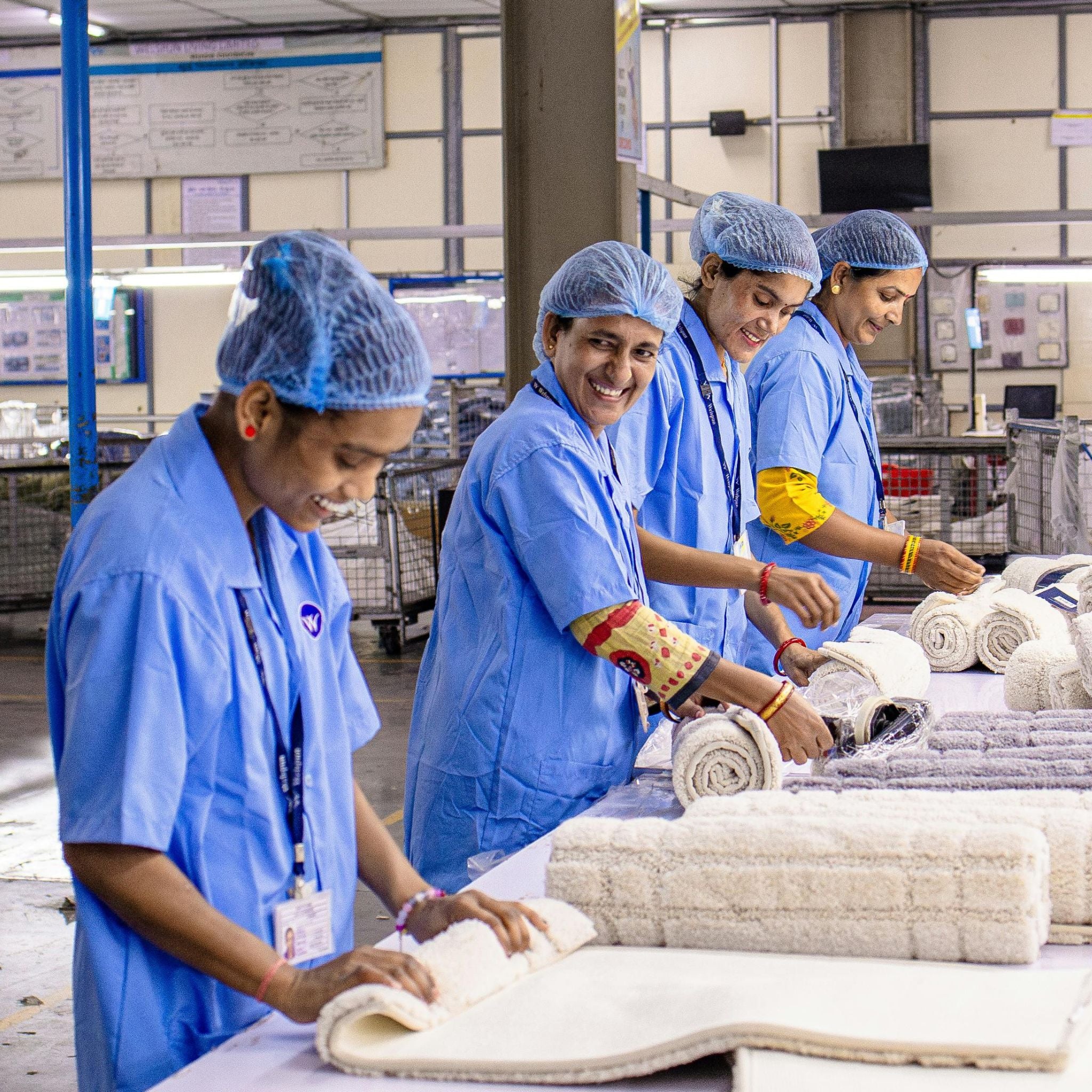 Workers in a factory setting handling fabric rolls.