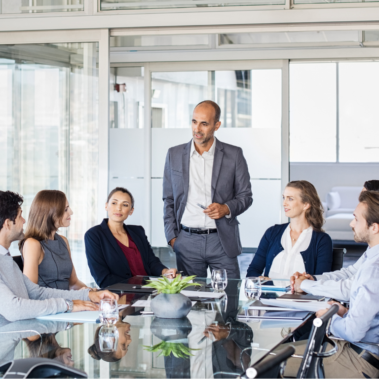 Group of people in a meeting room with a speaker addressing the group.