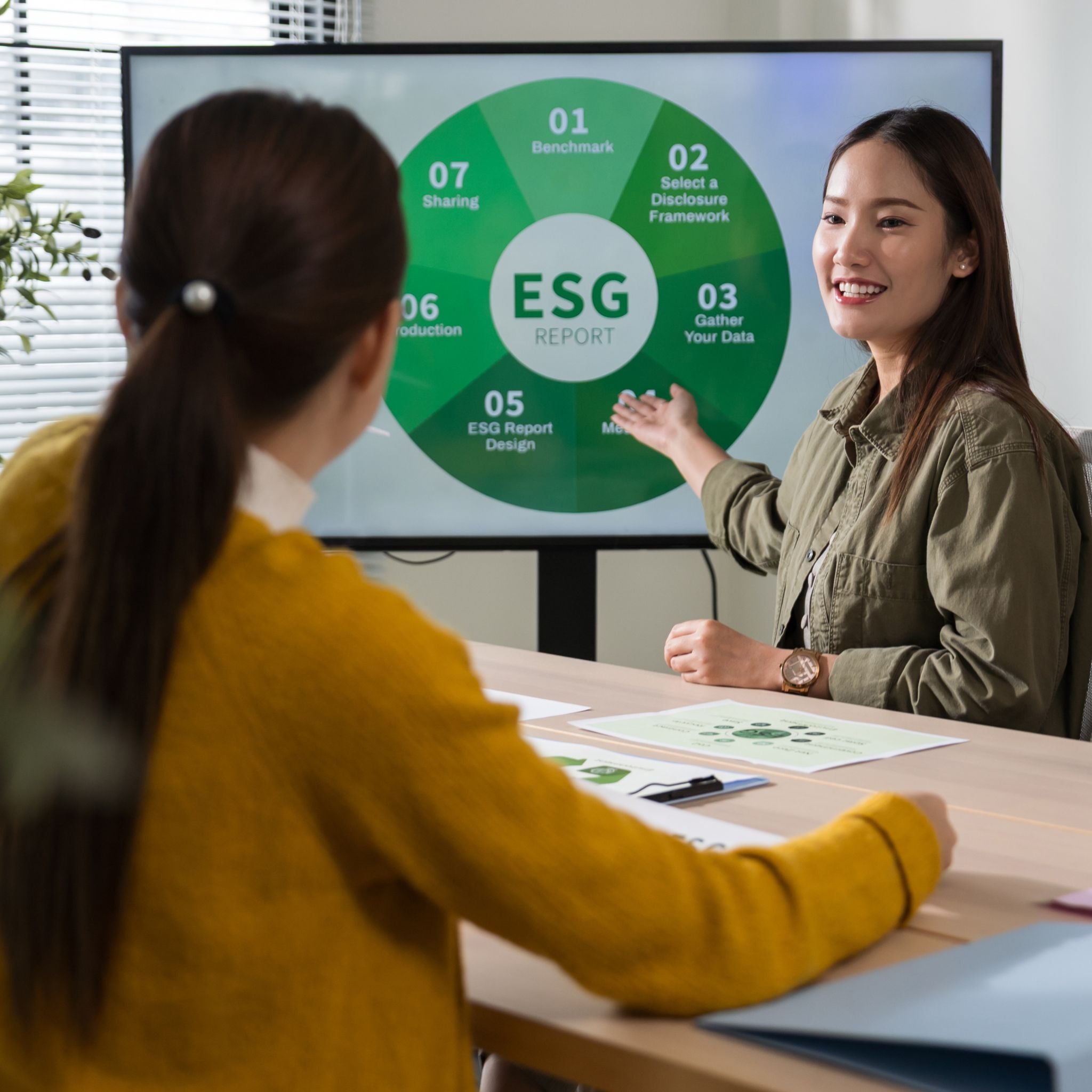 Two women discussing an ESG report in a meeting room 