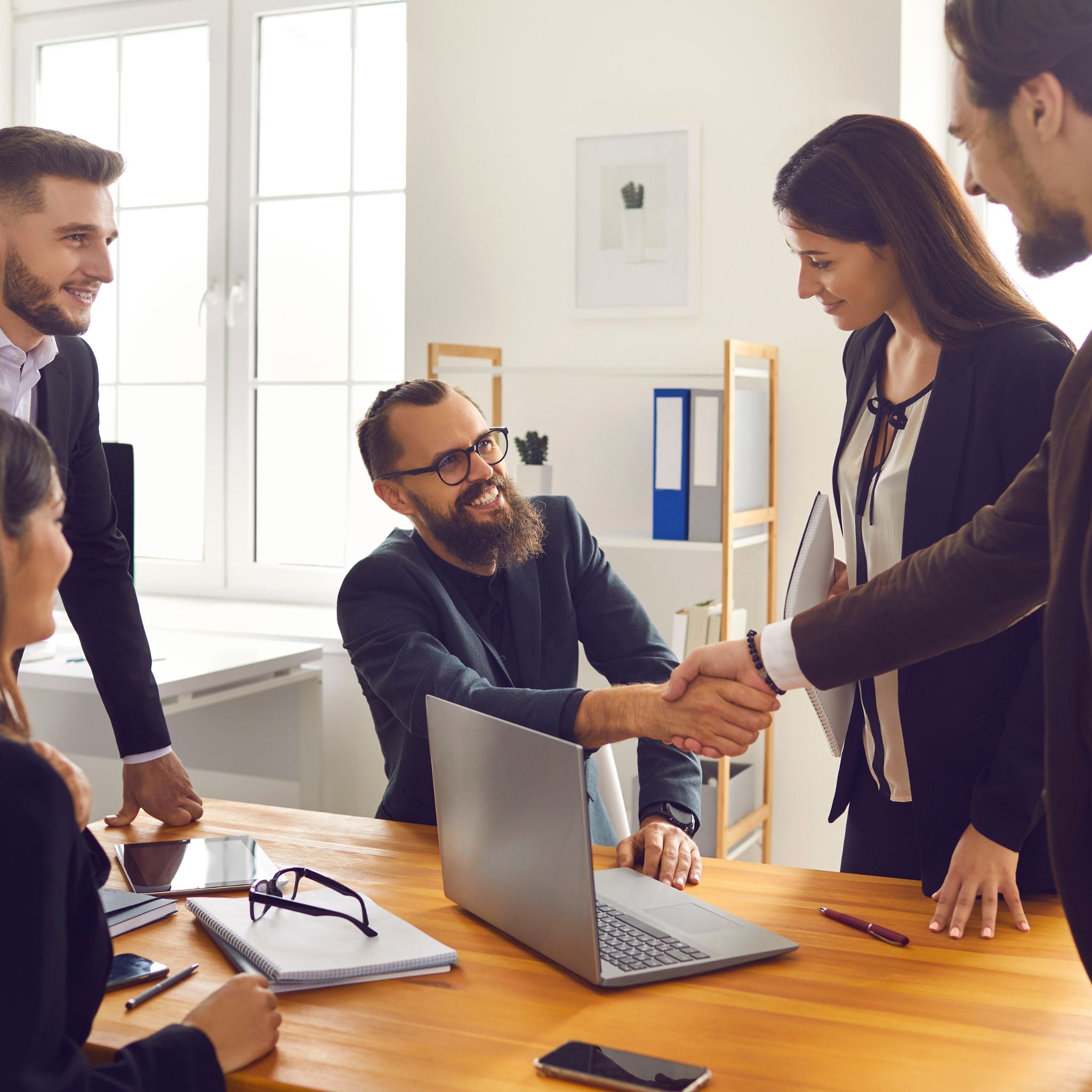 Business professionals shaking hands around a table in the office
