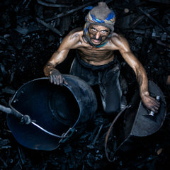 Man in a coal mine holding a bucket and surrounded by coal