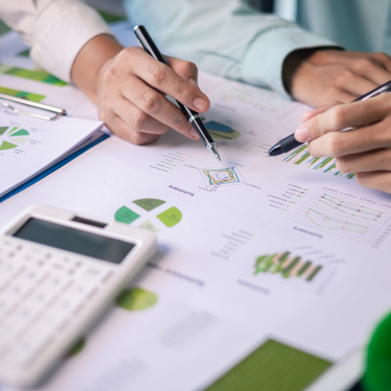 Two people working on financial documents with a calculator and pens